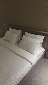 una cama grande con sábanas y almohadas blancas en Aurora desert camp wahiba sands, en Badīyah