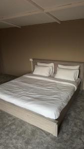 a large bed with white sheets and pillows at Aurora desert camp in Badīyah +23 photos