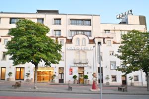 a large white building on a city street with trees at Hotel Bagoeira in Barcelos