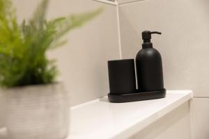 a black soap dispenser sitting on a shelf in a bathroom at Central Manchester Spacious Apartment with Free Parking in Manchester