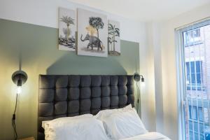a bedroom with a black headboard and three pictures on the wall at Central Manchester Spacious Apartment with Free Parking in Manchester