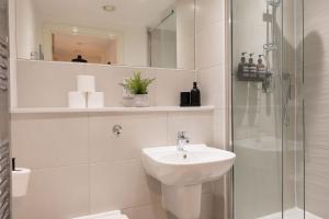 a white bathroom with a sink and a shower at Central Manchester Spacious Apartment with Free Parking in Manchester +15 photos