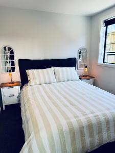 a bedroom with a bed with a striped comforter at Hiking Golf Skiing Lake Remarkables 7 Min Airport in Queenstown +12 photos
