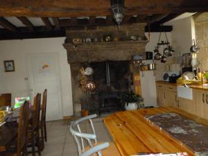 a kitchen with a wooden table and a fireplace at La Revaudiere in Bressuire