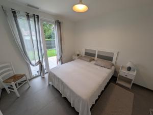 a bedroom with a bed and a chair and a window at Landaise in Messanges +14 photos
