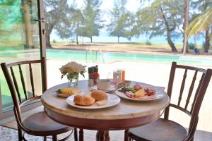 una mesa de madera con dos platos de comida. en Coriacea Beachfront Boutique Phuket Resort - SHA Plus en Mai Khao Beach