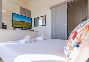 a bedroom with a white bed with a flat screen tv at Hostly-La Casa di Giada-Near Pisa, Lucca, Seaside in Navacchio