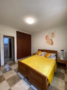 a bedroom with a large bed with a yellow bedspread at Appartement haut standing Mimboman in Yaoundé