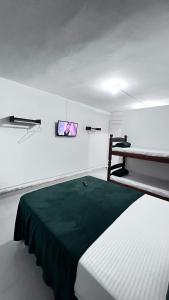 a bedroom with a bed with a green blanket at Quero mais arraial suites in Arraial do Cabo