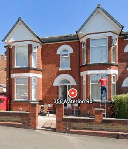 a man standing on the front porch of a brick house at Manchester Guesthouse in Manchester