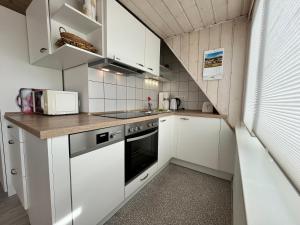 cocina pequeña con armarios blancos y fogones en Haus Moby Dick, en Wangerooge