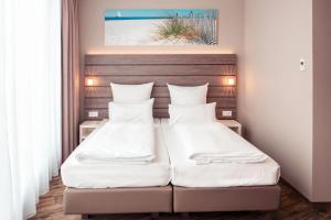 two beds in a small room with white pillows at Tulip Inn München Messe in Munich