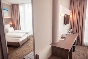 Hotelzimmer mit einem Schreibtisch und einem Sofa in der Unterkunft Tulip Inn München Messe in München + 37 Fotos