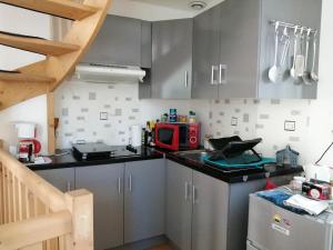 a kitchen with gray cabinets and a red microwave at Bord Charente face Pôle Magelis - T2b Triplex in Angoulême