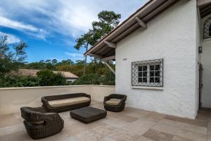a patio with wicker chairs and a couch at Maison de vacances, Piscine & Plage à pied in La Teste-de-Buch