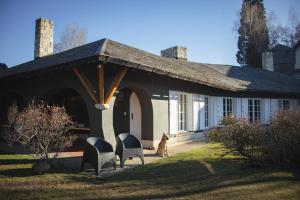 a dog sitting in front of a house at TEROTERO Lake Hostel - Habitación Mascardi in San Carlos de Bariloche