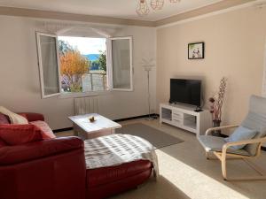 un salon avec un canapé rouge et une télévision dans l'établissement Maison proche Vaison la Romaine, à Saint-Romain-en-Viennois