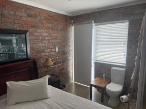 a bedroom with a bed and a brick wall at Classic Air B&B in Pearly Beach