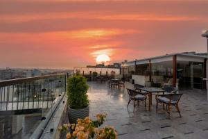 eine Dachterrasse mit Tischen und Stühlen bei Sonnenuntergang in der Unterkunft Pyramids Charm Hotel in Kairo