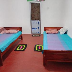 two beds in a room with mats on the floor at Leeostar Homestay & Safari in Horuwila