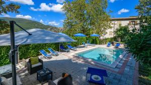 a pool with chairs and umbrellas next to a building at Acquanera 6&2 by Marche Holiday Villas in Piobbico