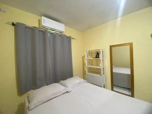 a bedroom with a white bed and a mirror at Casa Camargo - com mercado na frente in Campo Grande