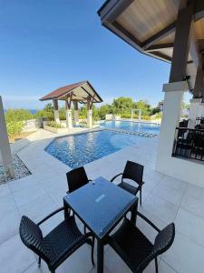 eine Terrasse mit Tisch und Stühlen neben einem Swimmingpool in der Unterkunft Peaceful Panglao Escape for Families & Couples in Dao