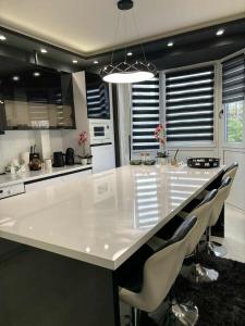 a kitchen with a large white island with chairs at Black&White Deluxe in Miskolc