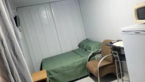 a room with a bed and a desk with a computer at Refugio Stella Container - Aconchegante, Completo e Bem Localizado in Brotas