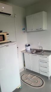 a small kitchen with a sink and a refrigerator at Kitnet Container - Prática e aconchegante in Brotas