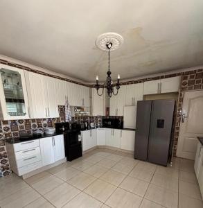 eine Küche mit weißen Schränken und einem schwarzen Kühlschrank in der Unterkunft Sunrise Serenity Lux Homes in Lilongwe + 5 Fotos