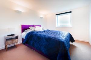 a bedroom with a blue bed and a window at Two Bedroom Flat by Brookland Stays Serviced Accommodation Short Lets London with Free WiFi in North Woolwich