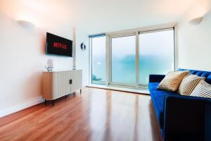 a living room with a blue couch and a large window at Two Bedroom Flat by Brookland Stays Serviced Accommodation Short Lets London with Free WiFi in North Woolwich