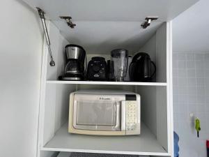 a microwave in a shelf in a kitchen at Flat no Condomínio Monte Castelo ao lado da área de lazer, Gravatá-PE in Gravatá