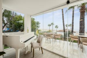 a white piano in a living room with glass walls at Home4u Mediterranean Sea Views Villa Alkaff in Manilva