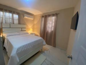 ein Schlafzimmer mit einem weißen Bett und einem Fenster in der Unterkunft apartamento moderno lo mejor de Santiago in Santiago de los Caballeros