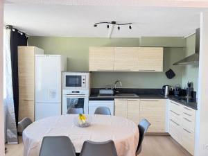 a kitchen with a table with chairs and a white kitchen at A l'orée des bois in Égat