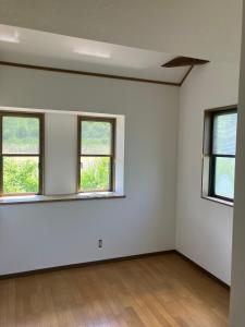 an empty room with three windows and a wooden floor at KijimaBase - Base 1 in Kijimadaira
