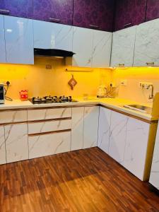 a kitchen with white cabinets and a stove top oven at Row House Near US Consulate BKC & NMCC in Mumbai