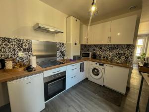 a kitchen with white cabinets and a washer and dryer at Cozy Air-Conditioned - Central - Close to Train Station in Brive-la-Gaillarde