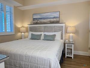 una camera da letto con un grande letto bianco con due lampade di Azure #404 Luxurious 4BD Beachfront Condo a Fort Walton Beach Altre 49 foto