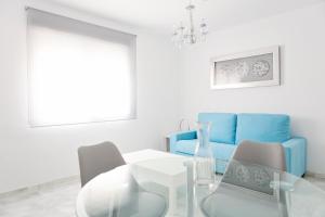 a white living room with a table and blue couch at Suncity Flat Salitre II in Málaga