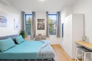 a bedroom with a couch and a desk and windows at 15 Minutes to NYC - A Fun & Colorful Getaway in Hoboken