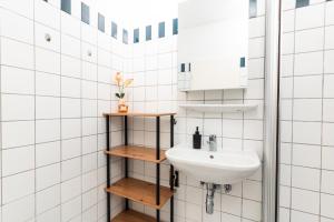 a white tiled bathroom with a sink and shelves at Im Herzen von Bad Ischl#3 in Bad Ischl