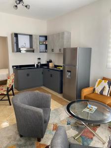 a living room with a table and a kitchen with a refrigerator at Mereri downtown appartments in Oranjestad
