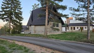 an old house with a black roof on a road at Sojka in Divčibare