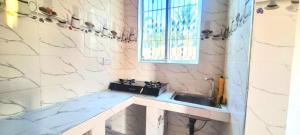 een badkamer met een wastafel en een raam bij Malkia Apartment in Kibigija