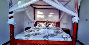 een slaapkamer met een rood en wit hemelbed bij Malkia Apartment in Kibigija