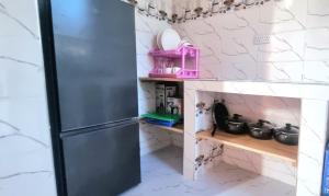 een keuken met een koelkast en een plank met potten en pannen bij Malkia Apartment in Kibigija +39 foto's