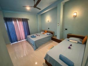 a bedroom with two beds and a large window at The Shore Residence in Hikkaduwa